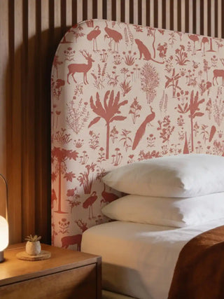 A bespoke curved headboard upholstered in Flora n Fauna rust velvet fabric featuring deer and peacock motifs in a modern bedroom.