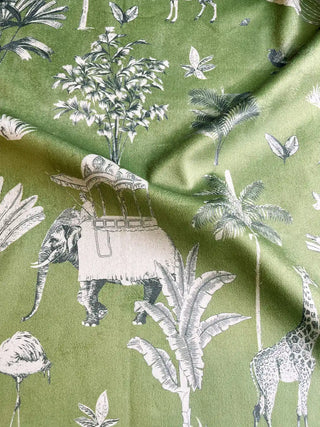 A high-resolution swatch of Itihaas design velvet in sage green, featuring detailed white illustrations of a flamingo, palm tree, and royal elephant.