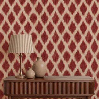 Wooden console table with a lamp and vases against a red and white patterned wallpaper.