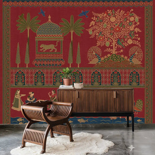 A red Indian-inspired wallpaper featuring ornate palace motifs, peacocks, tigers, trees, and traditional arches, styled behind a wooden console with chairs.