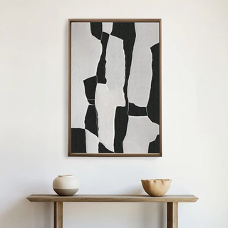 Modern European wall art in abstract black and white displayed above a console table with minimalist pottery décor.