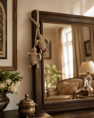 Beaded Kurma turtle charm draped over the corner of a wood-framed mirror