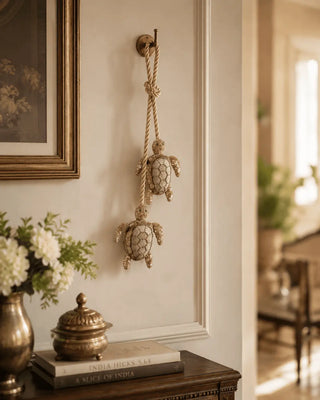 Pair of beaded Kurma turtle charms hanging from a brass hook in an entryway