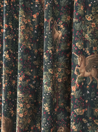 high-definition close-up of the intricate repeating central pattern of the Majestica curtain. The deep blue background serves as a canvas for detailed illustrations of fantastical creatures, including an ibex, a griffi...