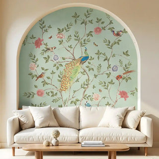 A decorative wallpaper inside a living room archway. The mural features a peacock, birds, and blooming branches on a pastel green background.
