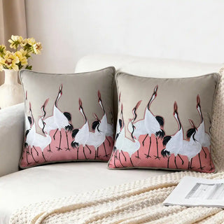 Sedge Pink Cushion Cover: Featuring embroidered cranes set against a soft pink fabric patch, it pairs beautifully with a warm beige base for a refined, modern contrast. Styled on a cozy neutral sofa.