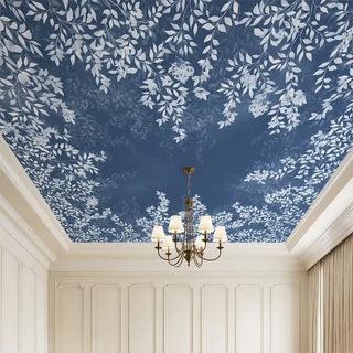 A luxurious ceiling wallpaper with white botanical foliage set against a rich blue background, styled in an elegant room with a chandelier and classic wall panels.