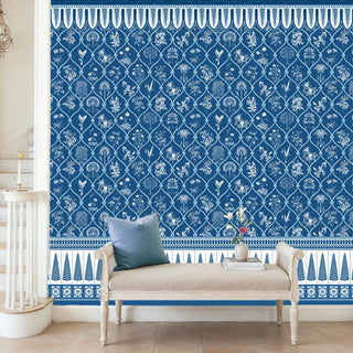 A blue and white wallpaper with intricate floral and geometric Mughal-inspired patterns, styled in a classic interior with neutral furnishings and minimal décor.