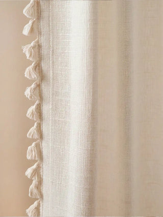 macro shot focusing on the side edge of the curtain panel. It beautifully highlights the rich, organic texture of the off-white linen base fabric and the delicate, small tassel lace trim meticulously attached to the b...