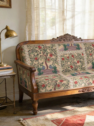A luxury vintage wooden sofa upholstered in Aakriti Beige & Red fabric featuring hand-painted peacocks and flowering trees.