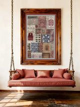 Aalishan wall art in a carved dark walnut frame hung above a traditional Indian wooden swing jhoola with rose-pink cushions and brass chain on a white wall