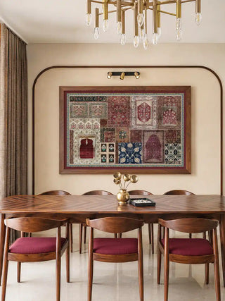 The framed Aalishan wall art displayed above a dining table beneath a chandelier, with wooden chairs upholstered in maroon.