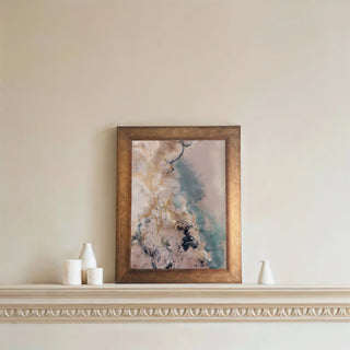 Abstract wall art framed in gold, hung above a decorative ledge with minimal white décor accents.