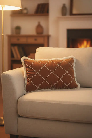 A luxury living room setting featuring the Amer Lattice lumbar cushion on a cream sofa by a cozy fireplace.