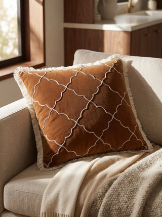 The Amer Lattice Mahogany cushion styled on a beige sofa in a sun-drenched, luxury interior setting.