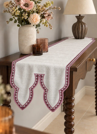 The Amrah Runner in Natural & Mauve runs the length of a dark wood console styled with a stone vase, amber glass candles and a carved wooden lamp base.