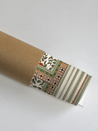 The Anant Madhubani wall art partially unrolled from its kraft paper shipping tube, showing the leaf-vine border and patterned edge.