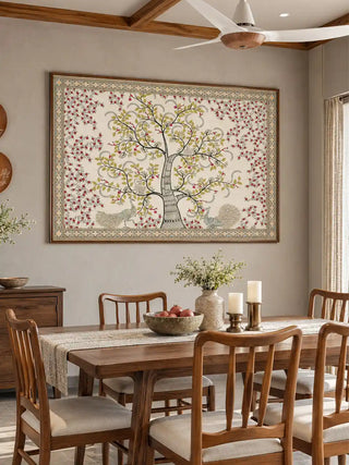 The framed Anant Vriksha wall art displayed above a dining table set with candles and a pomegranate bowl.