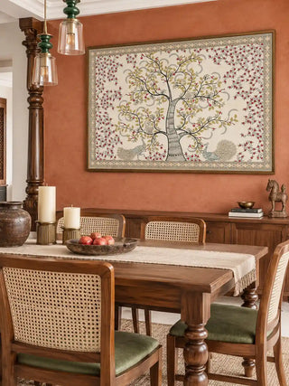 The framed Anant Vriksha wall art displayed above a wooden sideboard in a dining room with a terracotta-toned wall.