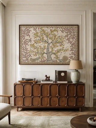 The framed Anant Vriksha wall art displayed above a mid-century wooden sideboard in a living room.