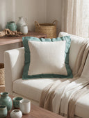Beige sofa with a decorative aqua frame cushion pillow cover, surrounded by home decor items on a wooden table.