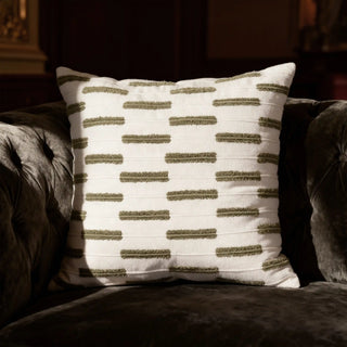 The Ari Garden cushion styled on a dark sage velvet armchair, showcasing how the texture catches the light in a luxury interior.