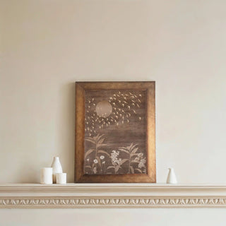 A framed abstract wall art with celestial motifs, displayed above a minimal white console on a neutral wall.