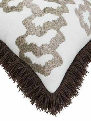 A close-up of the Aurea cushion cover corner showing dense radiating champagne stitches on an ivory woven ground, with a thick deep brown fringe along the edge.