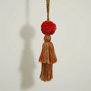 Close-up shot of the Autumn Flame Holdback hanging freely, showcasing the braided rope and the texture of the pom-pom and yarn.