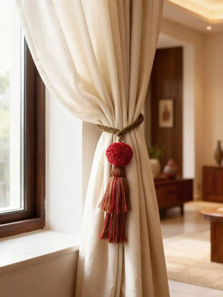 Beige curtain with a decorative red tassel and pom-pom- autum tieback from lifencolors in a room setting.