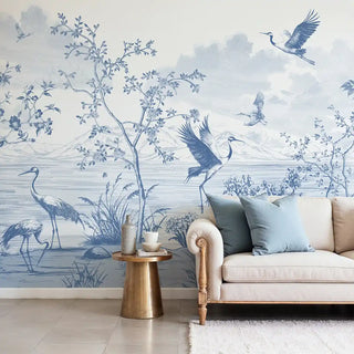 Full wall view of the Avian Garden blue and white mural with cranes, in a modern living room setting.