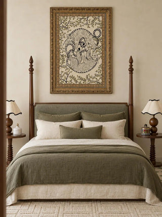 The Bagha Leela wall art in a gilt carved frame above a four-poster bed with olive and cream bedding and walnut side tables.