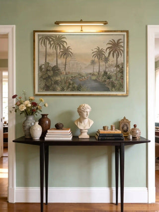 Large Bali wall art print styled in a dark frame on a sage green wall above a mahogany writing desk.