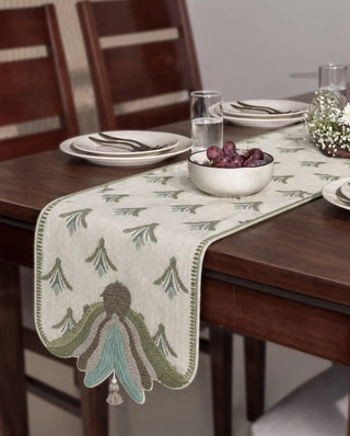 The Barg table runner's embroidered tassel end shown at a dining table with grapes and florals.