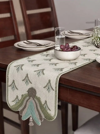 The Barg table runner in Sage & Teal laid down the centre of a dark wood dining table set with plates and a grape bowl.