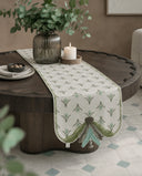 The Barg table runner in Sage & Teal styled on a round coffee table with a ribbed glass vase and lit candle.