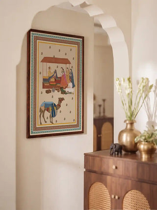 Framed Bazar Heritage wall art hung in a white arched hallway beside a wooden cabinet with brass vases