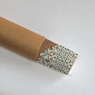 Bazar Heritage wall art in parchment, terracotta and teal partially unrolled from its kraft paper shipping tube, revealing the teal Iznik tile border and blue floral vine detail