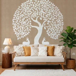 A beige wallpaper featuring a white Pichwai-inspired Tree of Life design with deer at the base, styled behind a modern sofa with cushions and decor.