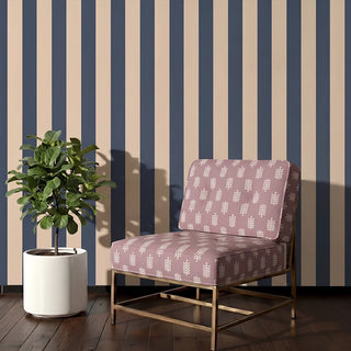Bloomark upholstery fabric in dusty rose on a brass-framed accent chair beside a fiddle leaf fig, against navy striped walls in a living room corner.