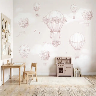 A vintage-inspired floral hot air balloon mural in soft pink behind a wooden play kitchen and small desk.