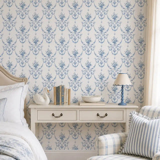 The Blue Garland wallpaper in Powder Blue & White installed on a feature wall in a bedroom behind a console-style nightstand with books and a ceramic swan. view-bedroom