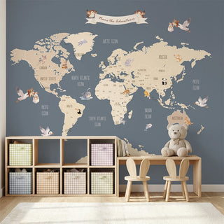 A luxury playroom setting featuring the Pastel Blue World Map mural behind a wooden desk and toy storage shelf.