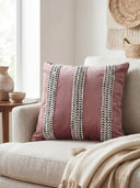 A luxury living room setting featuring the Blush Braid cushion on a cream sofa next to a wooden side table.