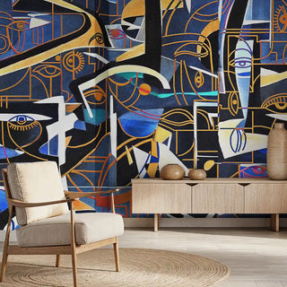 A bold abstract cubism-inspired wallpaper in deep blue, gold, black, and white tones, styled behind modern wooden furniture and a chair.