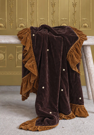 The Caramel Truffle sofa throw draped over a marble console table against gold art deco wallpaper.