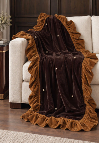 The Caramel Truffle sofa throw draped fully over a cream sofa in a dark-panelled living room.