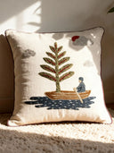 A luxury Celestial Village cushion cover featuring hand-embroidered landscape motifs and red piping on a tan velvet sofa.