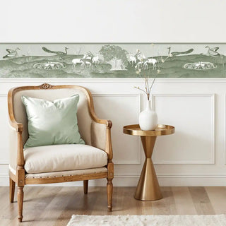 The Chandni Van sage green wall border styled above white wall paneling in a living room with a neutral bench and cushion.