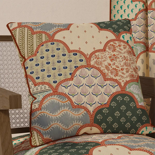 The "Chhap Pipin" cushion cover placed on a light wooden chair, showcasing its unique handcrafted style in a relaxed, home setting.